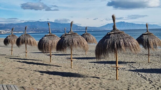 A beach with thatched umbrellas and a view of mountains in the background. - Villa with private infinity pool close to Port (AN)