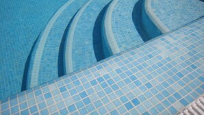 A swimming pool with blue tiled steps leading into the water. - Villa with private infinity pool close to Port (AN)