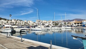 A marina with boats docked, a clear sky, and buildings in the background. - Villa with private infinity pool close to Port (AN)