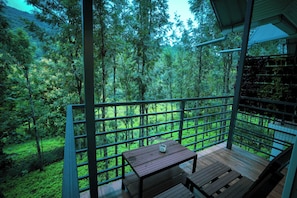 A balcony with a wooden table and bench, overlooking a forested area. - Misty Range Resorts, Marayoor (Devikolam)