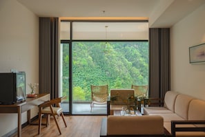 Una sala de estar moderna con un amplio ventanal corredera que da a un balcón, un sofá, una mesa de centro y un televisor.