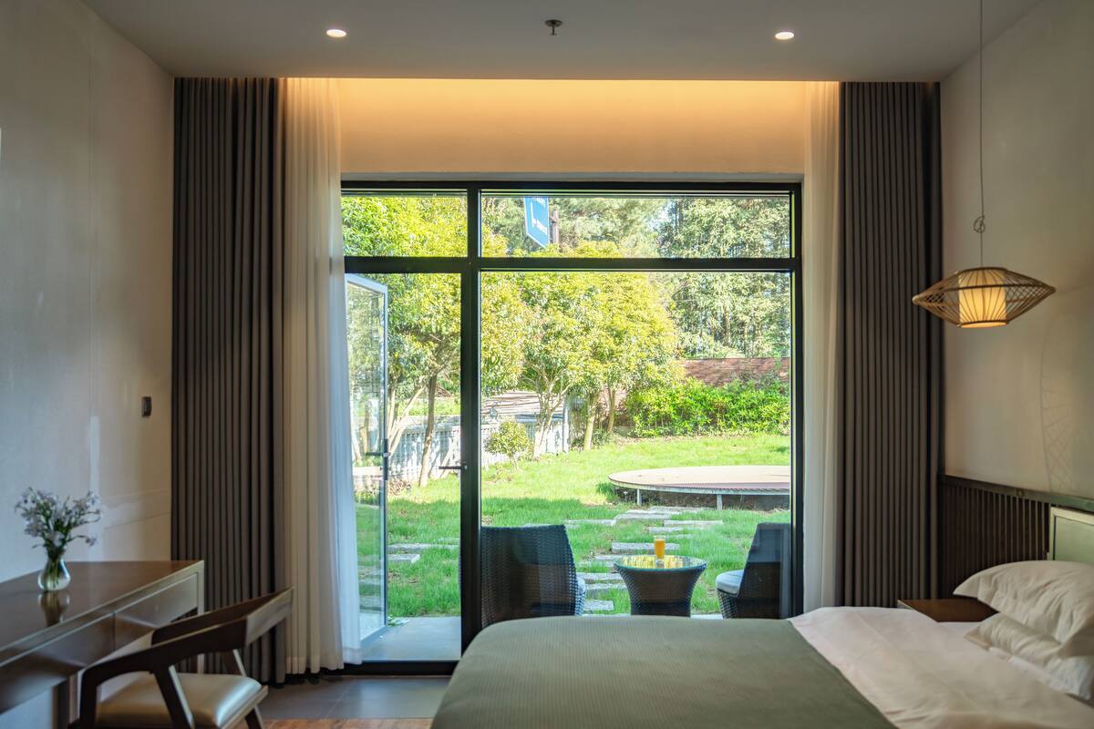 Une chambre avec une grande fenêtre, un lit, un bureau et une chaise.