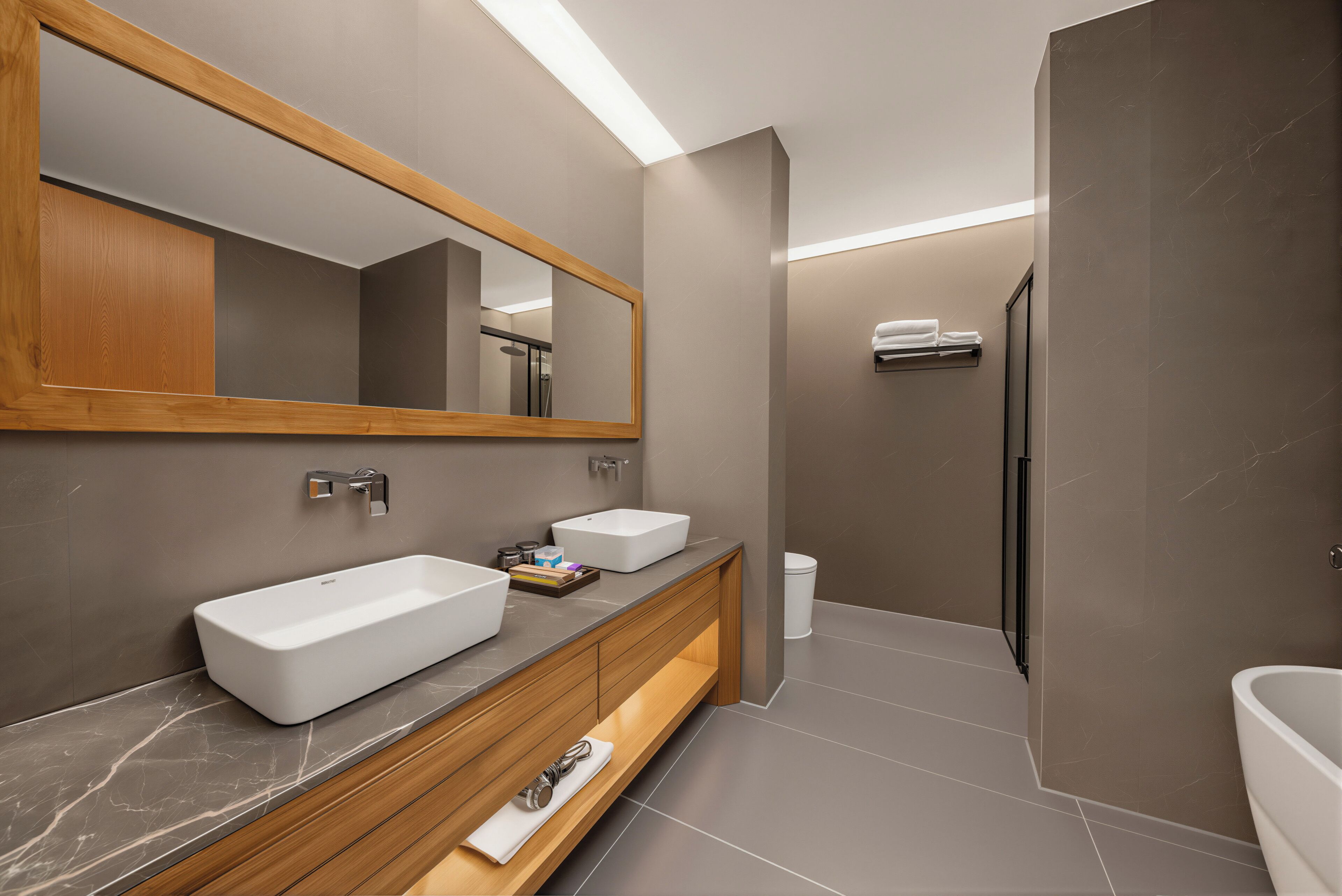A modern bathroom with a large mirror, two sinks, a shower, and a toilet.