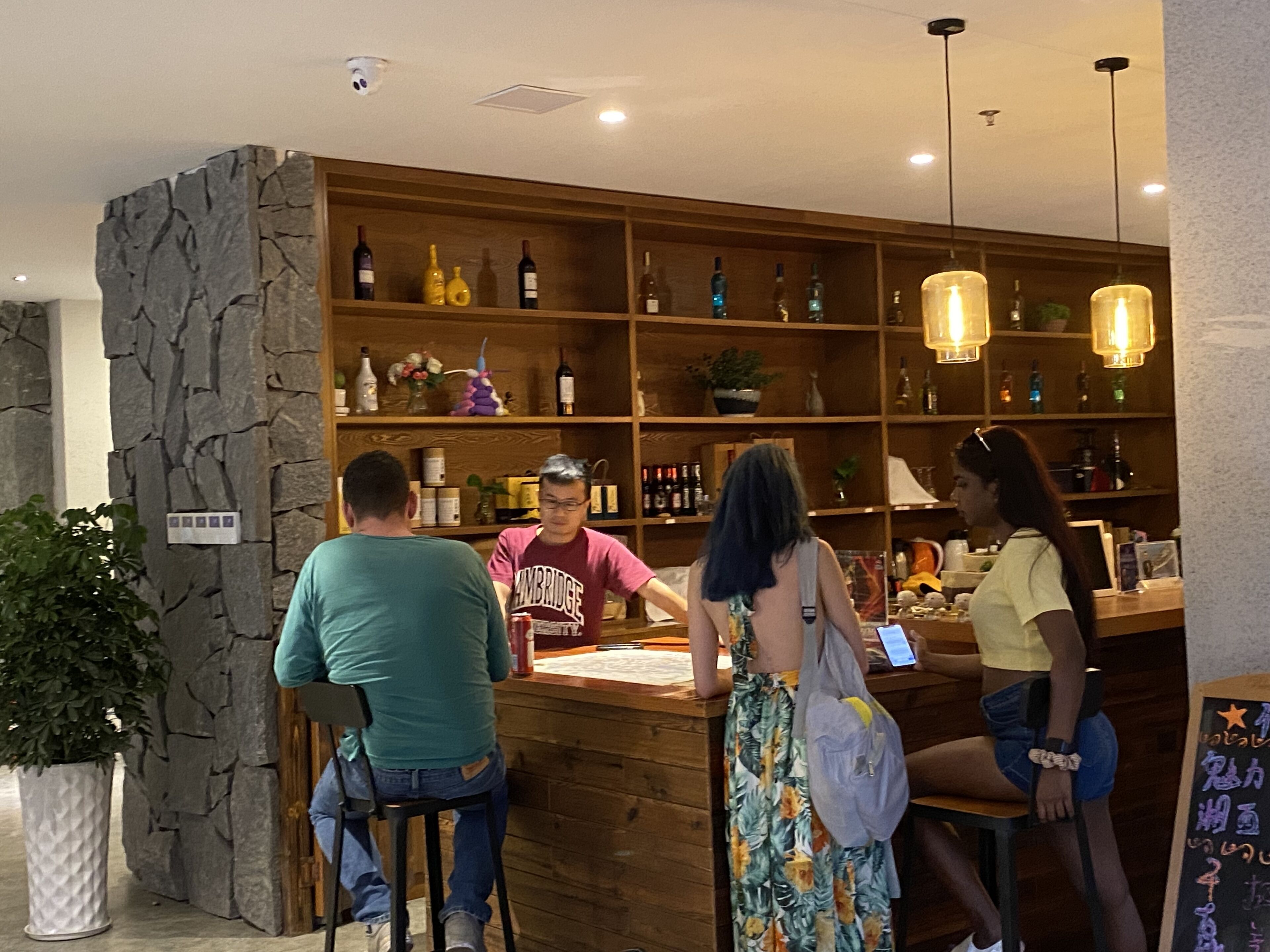 A bar area with wooden shelves stocked with bottles and a stone accent wall.