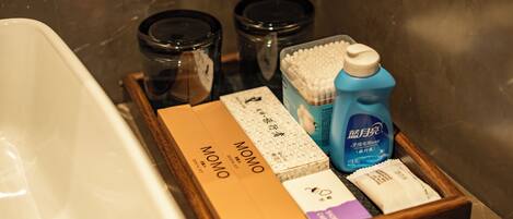 A bathroom with a bathtub, a wooden tray holding toiletries, and two black containers.