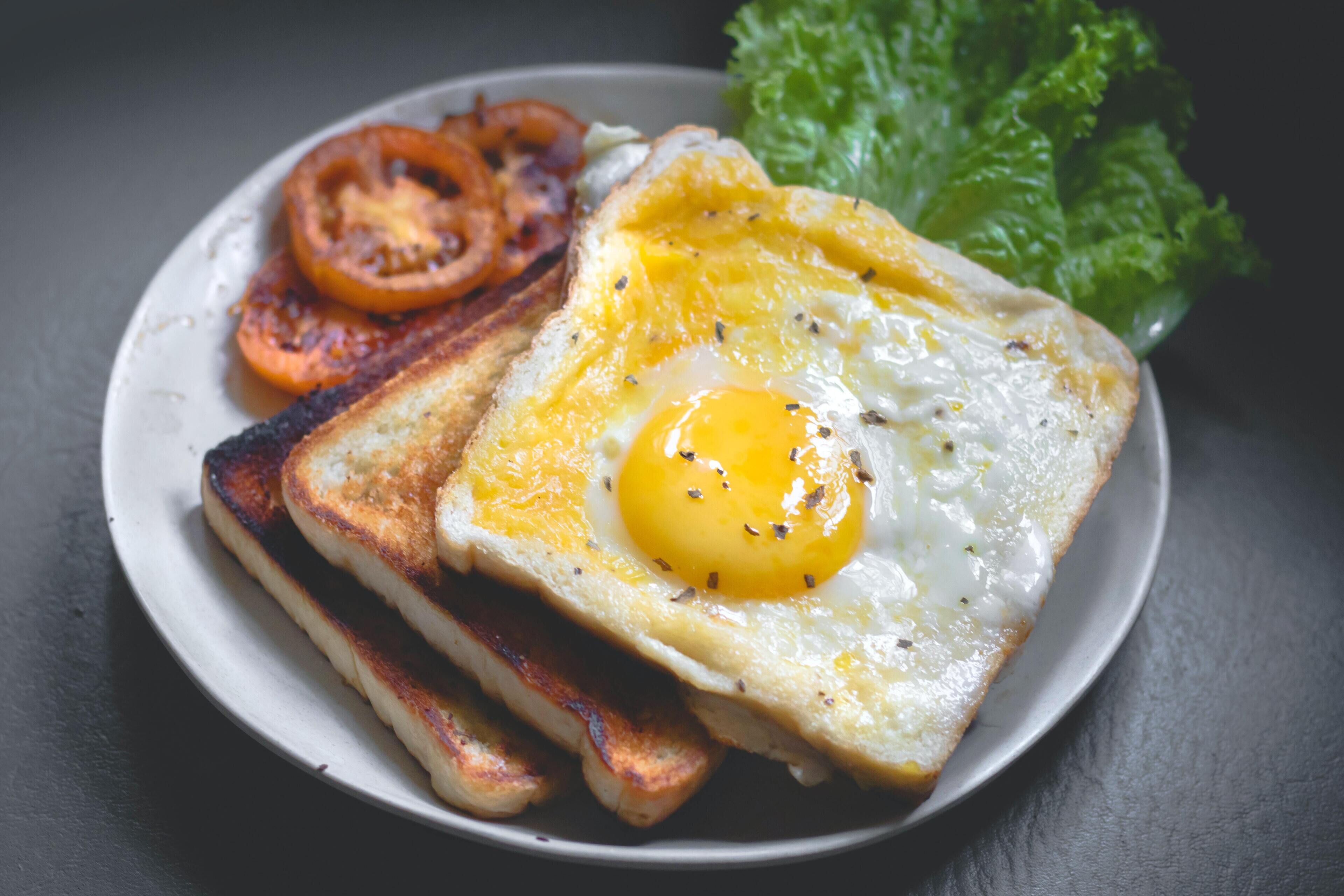A plate with a fried egg, toast, grilled tomatoes, and lettuce.