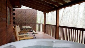 Un jacuzzi en una terraza de madera, con un cercado de madera y una mesa con sillas.