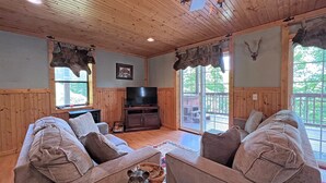 A cozy cabin interior with wooden walls, a television, and a dog statue on a coffee table.