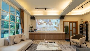 Ett modernt vardagsrum med en stor tv-skärm, bekväma sittplatser och utsikt över omgivningen.