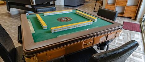 A pool table with stacked cubes, a billiards table, and a sofa in a room with a herringbone floor pattern.
