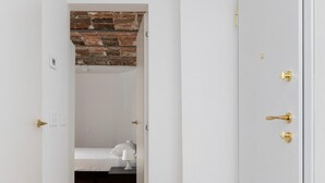 Un pasillo que conduce a un dormitorio con una pared de ladrillo decorativa, una cama y una mesita de noche.
