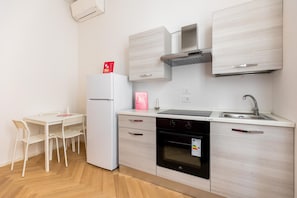 Eine kompakte Küche mit Kühlschrank, Backofen, Spüle und einem Essbereich mit Stühlen.