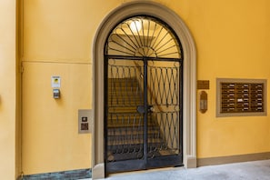 Um edifício amarelo com um portão de ferro preto e uma abertura para correspondência.
