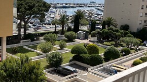 Un puerto deportivo con barcos, un área de estacionamiento y un edificio con balcón con vistas al puerto.