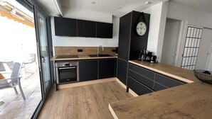 Una cocina moderna con armarios negros, encimera de madera y horno empotrado.