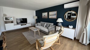 Una sala de estar moderna con un sofá, un televisor, una mesa de centro y una silla de madera.