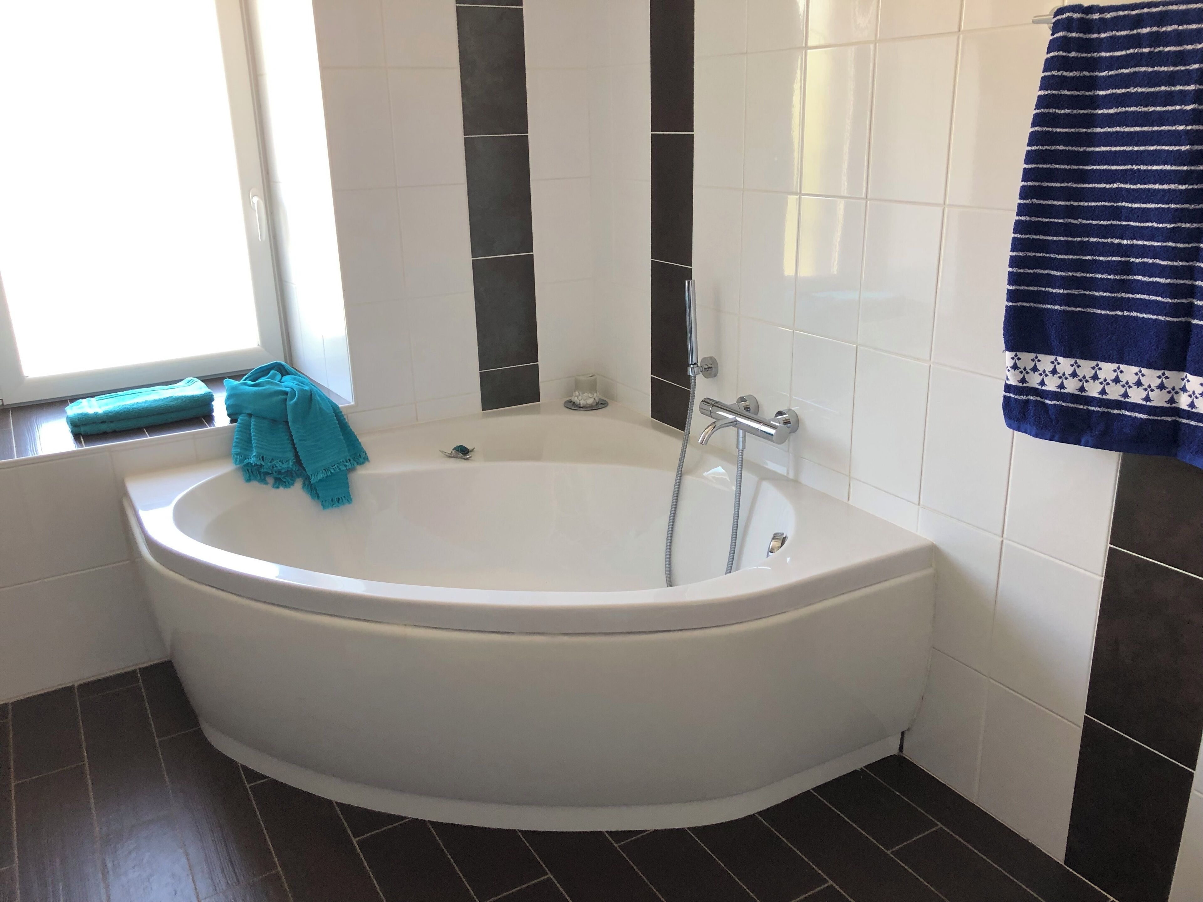 A modern bathroom with a freestanding bathtub, a window, and a towel rack.