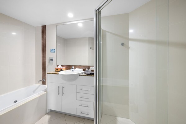 Un baño moderno con cabina de ducha de vidrio, una bañera blanca y un lavabo con encimera.