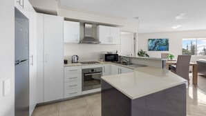 Una cocina moderna con armarios blancos, una campana extractora de acero inoxidable, microondas y horno empotrado.