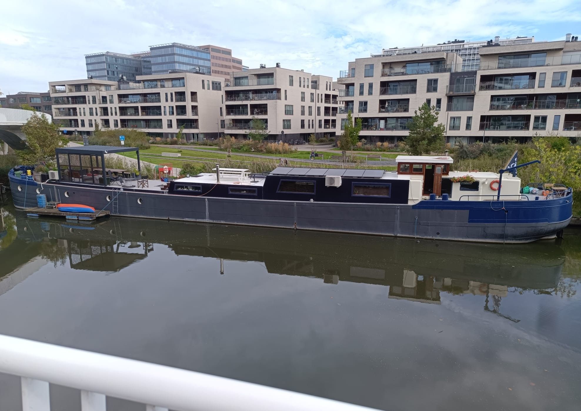 Un canal étroit, avec un grand bateau moderne amarré sur la rive droite.