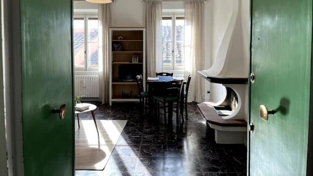 A room with a dining table, chairs, a bookshelf, and a green door. - At home in Oltrearno (Firenze)
