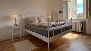 A bedroom with a single bed, bedside tables, a radiator, and a window with a view. - At home in Oltrearno (Firenze)