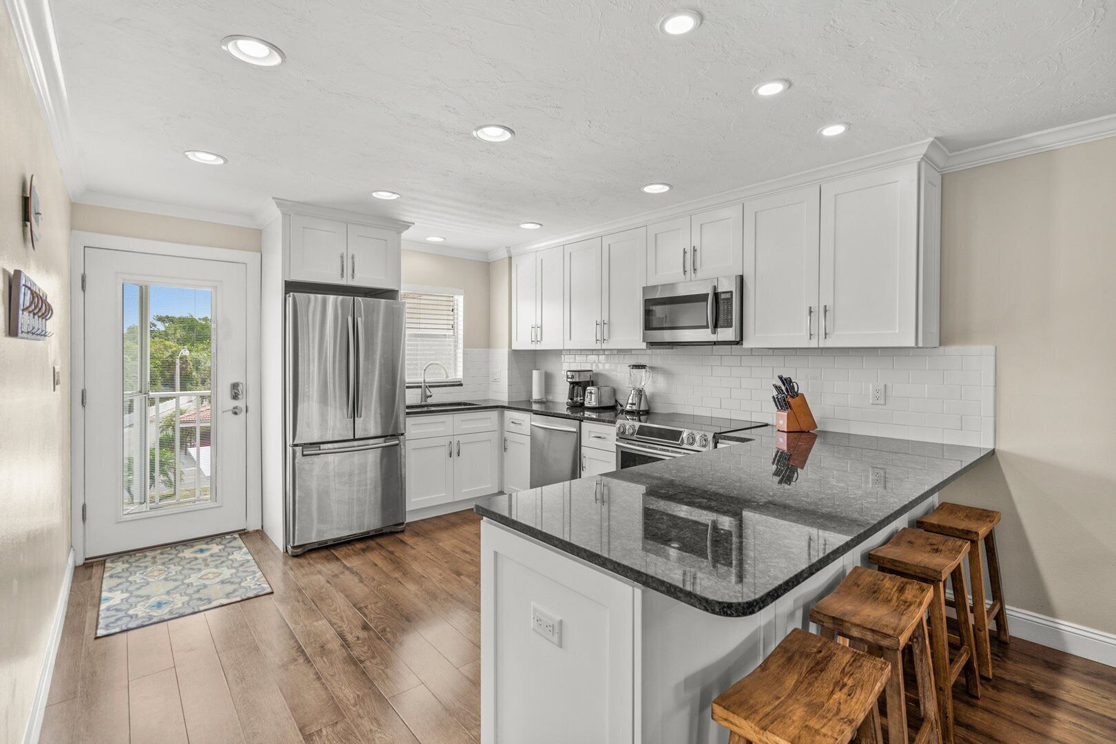 A modern kitchen with white cabinets, stainless steel appliances, and a granite countertop.