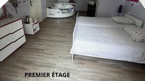 Ein Schlafzimmer mit Bett, einem kleinen Badezimmer und einer Whirlwanne. Der Raum hat eine schräge Decke mit einem Dachfenster.