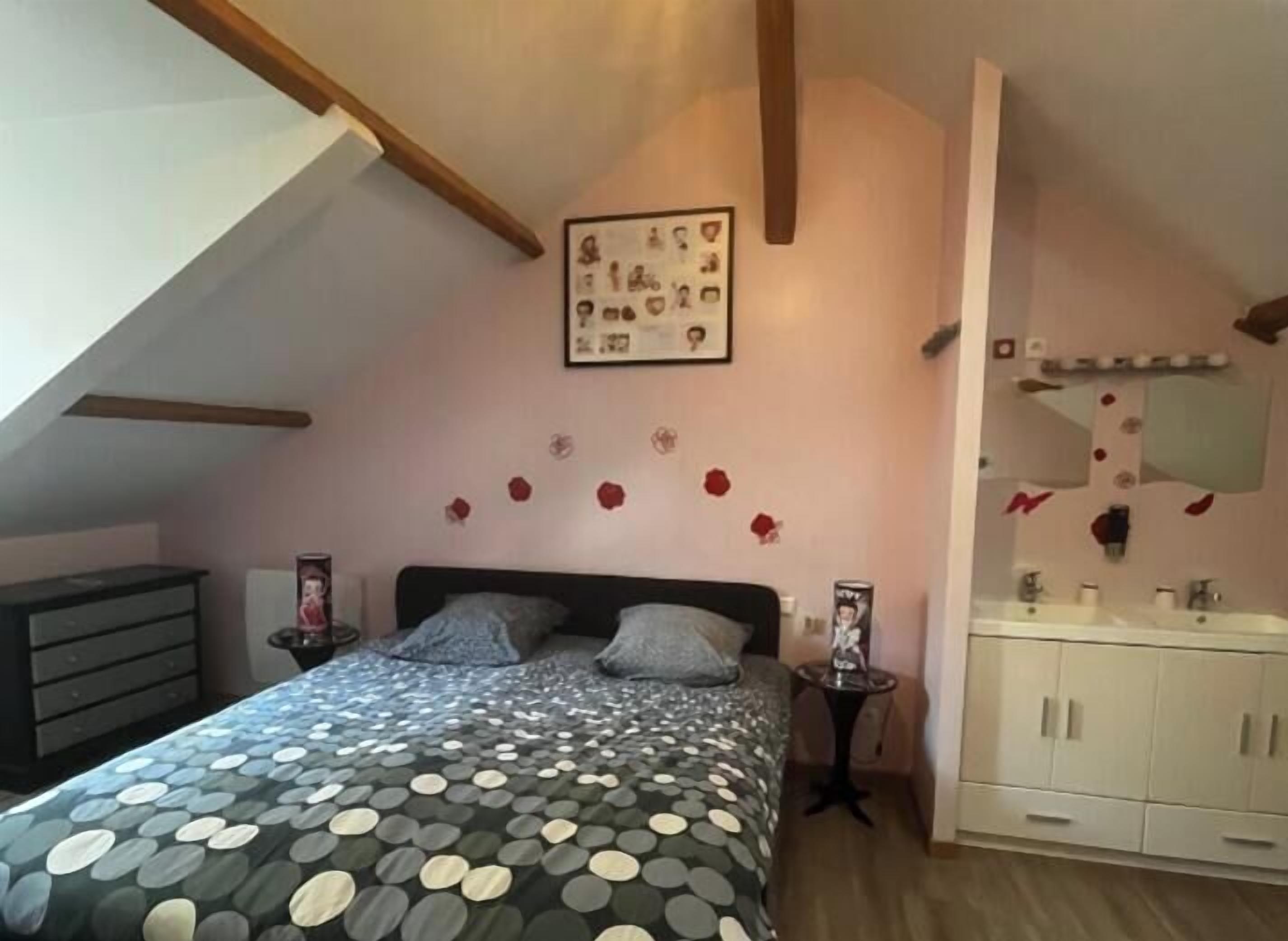 Een slaapkamer met een bed, een dressoir, een kaptafel met spiegel en een lijst met foto aan de muur.