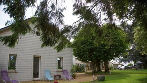 Ein Haus mit überdachter Terrasse, Rasenfläche und einem großen Baum.