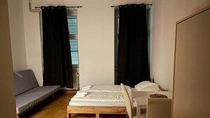 A compact room with a bed, a sofa, a small table, and a chair.