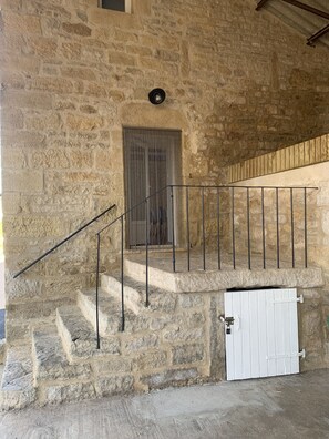 Una escalera de piedra con barandales de metal que lleva a una puerta con reja.
