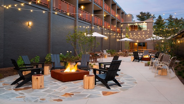 An outdoor patio area with seating, a fire pit, and string lights.