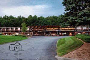 A modern hotel with a covered outdoor area, multiple floors, and a well-maintained lawn.
