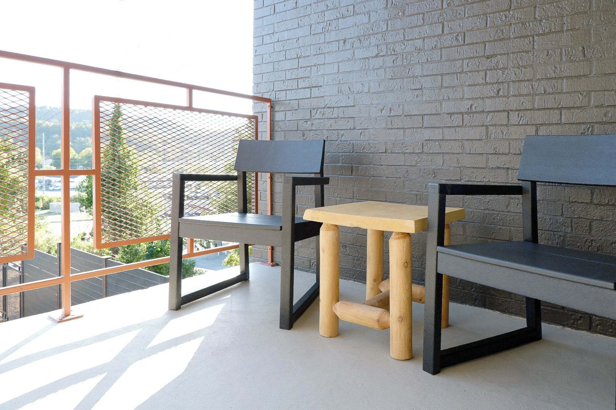 Ein Balkon mit Metallgeländer, zwei Holzstühlen und einem kleinen Tisch.
