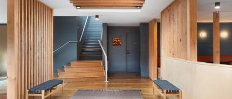 Ein modernes Interieur mit einer Holztreppe, Bänken und einem gemusterten Teppich.