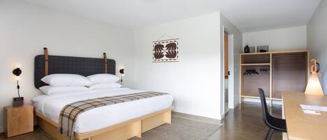 A modern bedroom with a bed, bedside tables, a desk, and a chair.