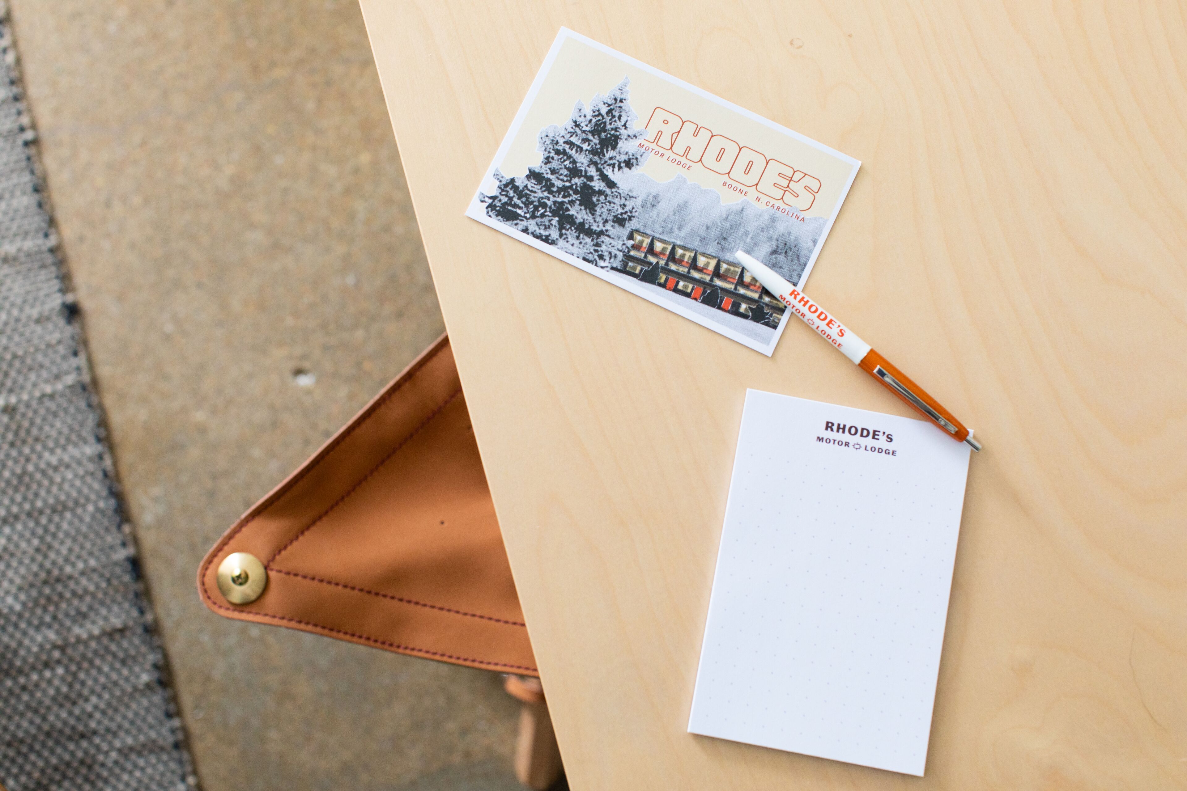 A notebook, a pen, and a brochure on a wooden table.