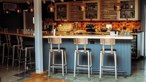 A bar area with a central island, bar stools, and shelves stocked with bottles and glasses.