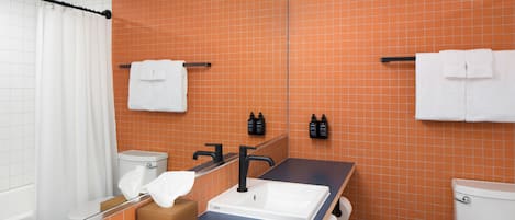 A bathroom with orange tiled walls, a white sink, a black faucet, and a bathtub.