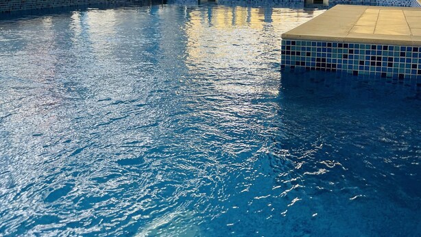 Una piscina interior con agua cristalina, un flotador salvavidas y un cartel en la pared.