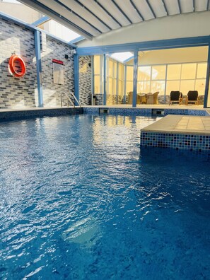 An indoor swimming pool with clear water, a lifebuoy, and a sign on the wall. - Grand Legacy Hotel Doha (Doha)