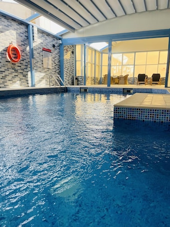 Una piscina techada, sillones reclinables de piscina