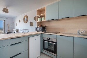 Une cuisine moderne avec des meubles de couleur bleu clair, un four encastré, un évier et des éléments décoratifs sur les murs.
