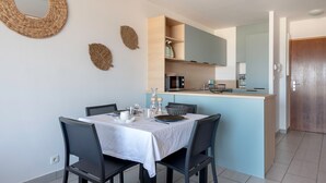 A modern kitchen with a central island, a dining table with chairs, and a large mirror above the island. - Facing the sea -  apartment for 2 (Saint-Brevin-les-Pins)