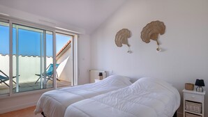 A bedroom with a large bed, a nightstand, a lamp, and a wall decoration. - Facing the sea -  apartment for 2 (Saint-Brevin-les-Pins)
