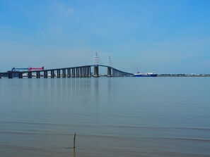 Un long pont enjambant une étendue d’eau calme, avec un navire visible au loin.