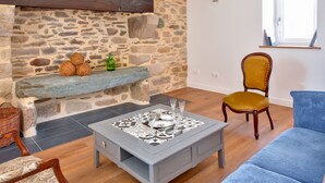 Ein Wohnzimmer mit Kamin aus Stein, einem Couchtisch mit dekorativer Tischplatte, einem blauen Sofa und einem Holzstuhl.