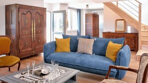 Ein Wohnzimmer mit blauem Sofa, Holzschrank und einer Treppe.