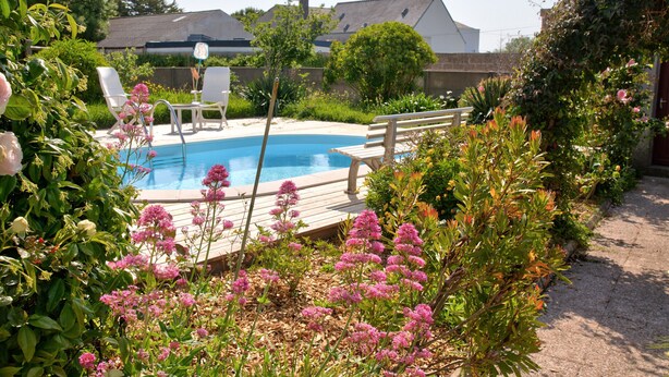 En baghave med swimmingpool, træterrasse og udendørs siddeområde.